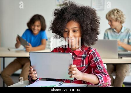 Buona ragazza africana scuola utilizzando il computer tablet digitale in classe. Foto Stock