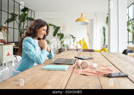 Giovane donna d'affari latino-americana in una riunione online utilizzando un computer portatile. Lavoratore di ufficio femminile in videochiamata che lavora da casa. Foto Stock