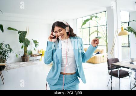 Felice donna d'affari in tuta formale ballando motivato a celebrare i successi di lavoro in ufficio. Donna che lavora che si diverte sul posto di lavoro. Foto Stock