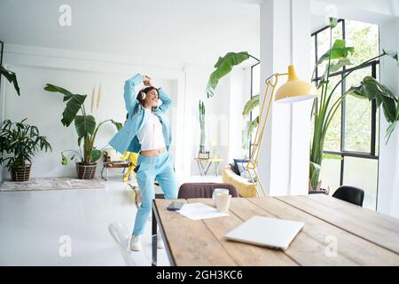 Felice allegro giovane attraente donna d'affari in abito formale danza vittoria danza in ufficio a casa. Lavoratore di ufficio femminile che si diverte sul posto di lavoro. Foto Stock