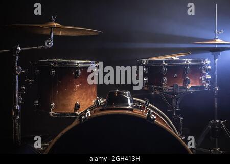 Parte di un drum kit su sfondo nero, percussione strumento, tamburo snare, basso tamburo, hi-Hat sul palco sotto i riflettori. Foto Stock