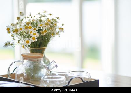 Bellissimi fiori bianchi a margherita in un vaso di vetro sul tavolo da cucina vicino alla finestra. Composizione floreale in casa, arredamento. Foto di alta qualità Foto Stock