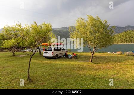 Un turista, madre e figlio, rilassarsi in un campeggio sulla riva di un bacino di Vau Dejes sul fiume Drin in un bellissimo giorno d'estate, Albania Foto Stock