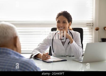 Felice ottimista medico femminile in cappotto bianco dando consulenza Foto Stock