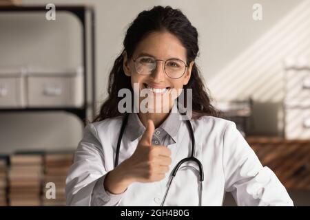 Testa colpo ritratto di felice medico GP femmina mostrando come Foto Stock