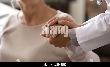 Medico femminile in mano bianca di tenuta del paziente anziano Foto Stock
