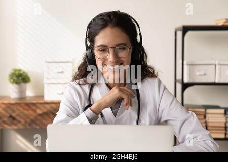 Buon medico amichevole in cuffie chiacchierando con il paziente Foto Stock