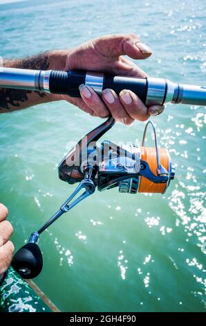 Primo piano di mani che tengono una canna da pesca al molo Deal nel Kent Inghilterra UK Foto Stock