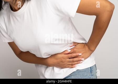 La donna malata che tocca il lato sinistro soffre di dolore addominale acuto nello stomaco, nell'appendice o nella pancreatite Foto Stock