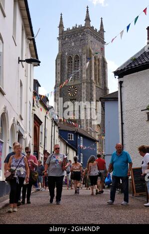 Persone che camminano lungo una strada acciottolata con la torre della chiesa di San Pietro e Paolo sullo sfondo a Cromer Norfolk Foto Stock