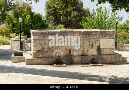 Abbonati la fontana di Pyli Spring con 6 sculture di gargoyle di una testa di leoni che sputano acqua di sorgente attraverso un ugello. Pyli villaggio, Kos, Grecia. Foto Stock