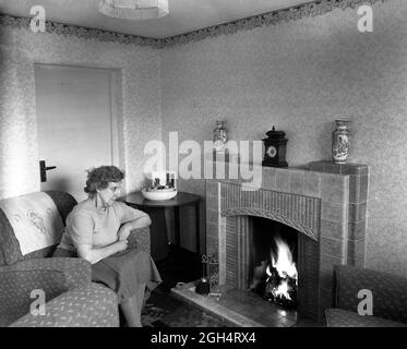 Casa dolce casa anziana donna seduta accanto al suo fuoco di carbone in una casa del consiglio Gran Bretagna 1952 Foto Stock