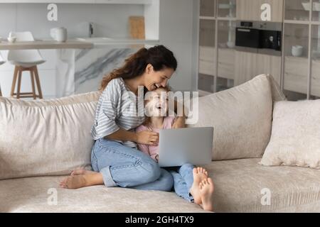 Felice madre giovane e figlia piccola guardando fumetti divertenti. Foto Stock