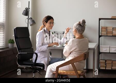 Sorridendo medico giovane dando consiglio, parlando con la donna anziana Foto Stock