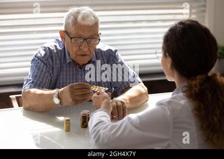 Confuso anni 80 paziente di sesso maschile che prende pillole dal medico GP Foto Stock