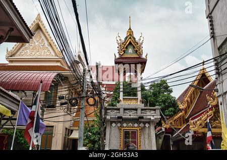 Bangkok, Thailandia 04.28.2021 Guardian Nagas, bandiere ed edifici colorati decorati segnano l'entrata della strada al Wat Nak Prok, il Tempio di Naga. Foto Stock