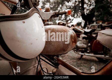 Canotta arrugginita su ciclomotore antico con casco bianco sul manubrio, nostalgia Concept Foto Stock