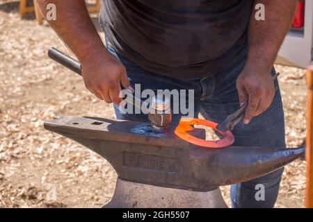 Un fabbro, un guerriero, che crea e forma un ferro di cavallo su un incudine, con un martello, la Spagna. Foto Stock