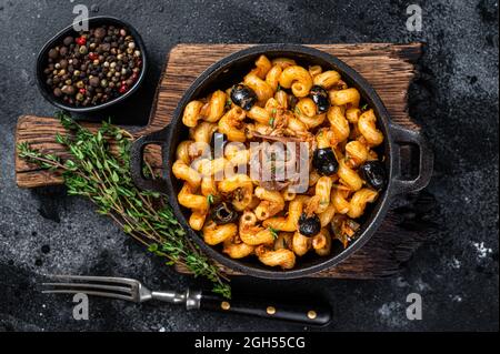 Pasta Cellentani Puttanesca Pasta di pesce in padella. Sfondo nero. Vista dall'alto Foto Stock