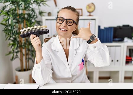 Giovane donna caucasica che tiene i denti bianco tavolozza sorridendo facendo il gesto del telefono con la mano e le dita come parlare al telefono. Comunicazione c Foto Stock