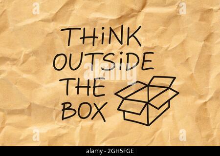 Testo Think outside the Box scritto a mano su carta marrone grattata. Creatività o concetto di innovazione. Foto Stock