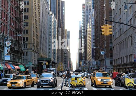 New York, Stati Uniti d'America - 21 novembre 2010: Le persone cavalcano taxi gialli lungo la 6th Avenue. Ci sono stati 13,237 taxi gialli registrati a New York City. Foto Stock