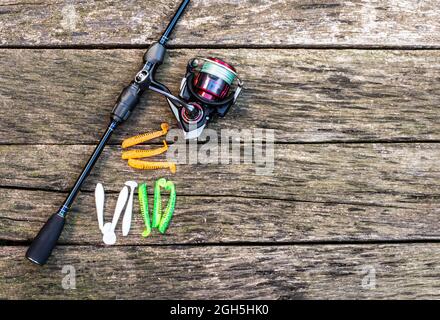 Attrezzatura da pesca - canna da pesca, lenza, ganci e esche su sfondo di legno Foto Stock