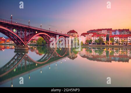 Maribor, Slovenia. Immagine del paesaggio urbano di Maribor, Slovenia all'alba estiva con riflessi della città sul fiume Drava. Foto Stock