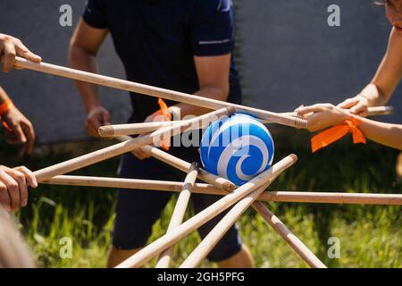 Gioco di teambuilding per gruppi di persone per ottenere lo spirito di squadra e aumentare l'amicizia per i colleghi. Gioco di squadra con palla e bastoni. Foto Stock