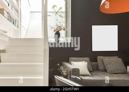 Il design interno dell'area salotto con comodo divano e poltrona in pelle è un moderno appartamento con pareti bianche e nere Foto Stock