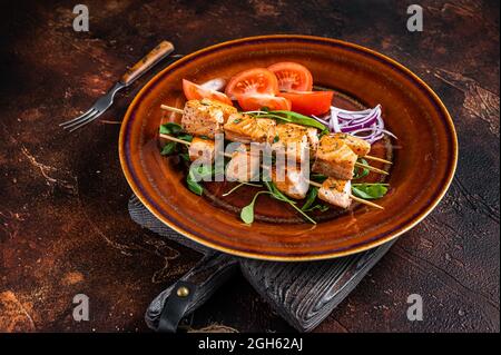 Spiedini di salmone al barbecue kebab su piatto rustico con verdure. Sfondo scuro. Vista dall'alto Foto Stock