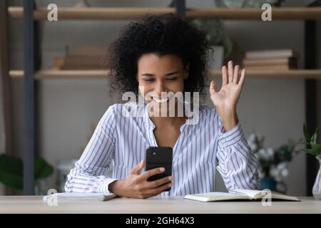 Sorridente ragazza biraciale prendere pausa nel lavoro facendo videocall Foto Stock