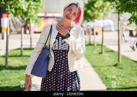 Da sotto giovane donna trendy proprietario con capelli tinti in elegante giacca di pelle e cappello abbracciando adorabile cane Golden Retriever mentre si siede su pietra ben Foto Stock
