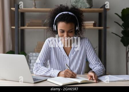 Giovane donna nera impegnata in cuffie per l'apprendimento a distanza Foto Stock