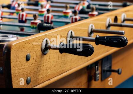 Particolare di calcio da tavolo retrò con figurine in legno in miniatura di giocatori su barre metalliche Foto Stock