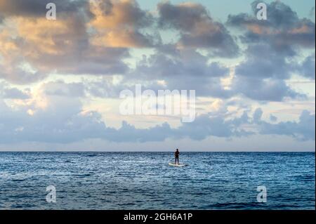 Il solitario paddleboarder galleggia lontano dalla riva dell'isola di Oahu, Hawaii Foto Stock