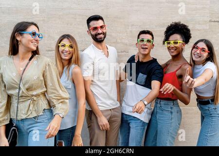 Persone felici con occhiali che si divertono sorridendo contro un muro Foto Stock