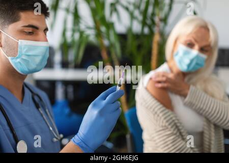 Donna anziana vaccinata contro il Coronavirus seduto al Centro medico Foto Stock