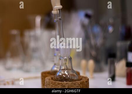 Matraccio a fondo tondo con gocciolatore in gomma di vetro per sintesi chimica avanzata in un laboratorio di chimica con sostanze chimiche in fiale Foto Stock