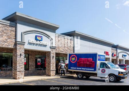 OLEAN, NY, USA-14 AGOSTO 2021: Rent-A-Center store, mostra deposito, camion consegna, due uomini consegna scarico divano. Foto Stock