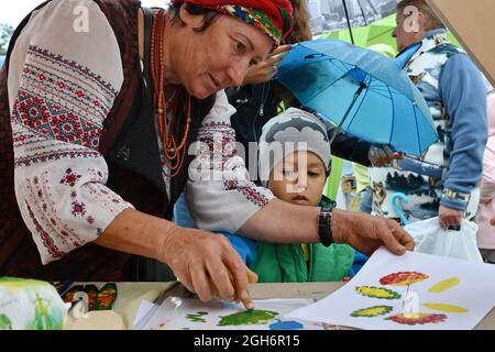 Kramatorsk, Ucraina. 4 settembre 2021. Un artista in abbigliamento tradizionale che mostra a un ragazzino come dipingere durante il festival etnico a Kramatorsk. Il 6 ths festival etnico dell'arte dilettante dedicato al pittore ucraino di arte popolare e artista di arte ingenua Maria Prymachenko. L'Ucraina è famosa per le sue tradizioni vivaci e la dinamica vita culturale, che attrae sempre più visitatori in questo bellissimo paese. Credit: SOPA Images Limited/Alamy Live News Foto Stock