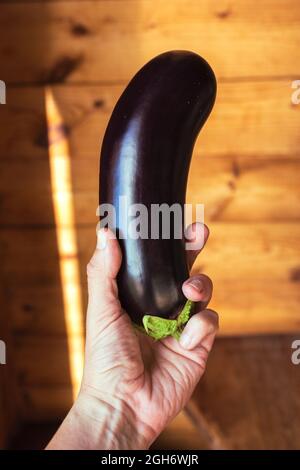 Mano con melanzane su sfondo di legno. Zdorovoye pitaniye Foto Stock