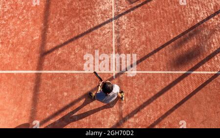 Vista dall'alto di un giocatore di paddle tennis in attesa della palla in una partita su un campo all'aperto. Foto Stock