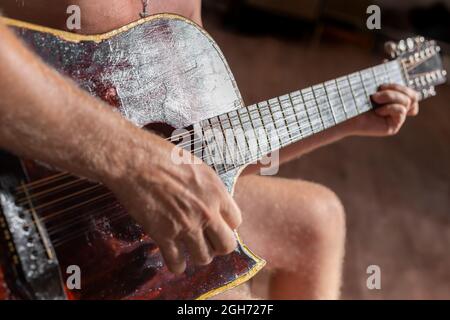 Un uomo suona una chitarra acustica a dodici corde. Hobby e intrattenimento. Foto Stock