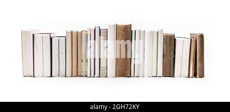 Assortimento di libri nuovi e vecchi in fila isolati su sfondo bianco. Foto Stock