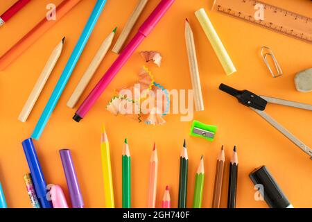 Concetto creativo di forniture scolastiche su sfondo arancione. Bentornato a scuola. Vista dall'alto. Disposizione piatta. Foto Stock