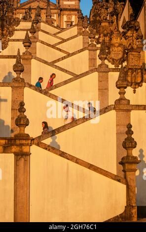 Immagine astratta della scala a forma di zig zag della chiesa con turisti occasionali che saliscono e scendono - Bom Jesus do Monte, Braga, Portogallo, verticale Foto Stock