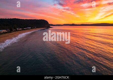 Alba al mare con cielo pieno di nuvole e due persone in kayak da surf da Pearl Beach sulla costa centrale, NSW, Australia. Foto Stock