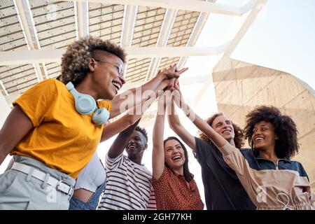 Gruppo di giovani che si accatastano mano. Gruppo multietnico di studenti che festeggia all'aperto. Foto Stock
