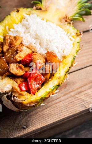 Pollo fritto con riso a metà ananas sullo sfondo rustico. Messa a fuoco selettiva. Profondità di campo poco profonda. Foto Stock